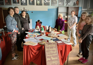 Uczniowie i goście stoją w sali języka polskiego w której widać rekwizyty teatralne