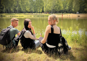 Trzech uczniów siedzi nad stawem w Arturówku