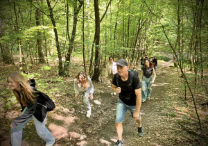 Uczniowie wraz z nauczycielem idą przez las