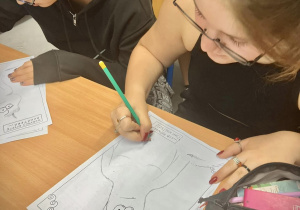 Uczennice podczas warsztatów uzupełniają komiks rysunkami