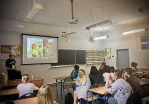Uczniowie siedzą w ławkach oglądając prezentacje naszego gościa