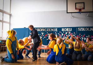 Minionki klęczą na podłodze a pani dyrektor Katarzyna Mielech wciela się w rolę Lucy Wild
