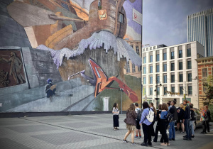 Uczniowie podziwiaja najstarszy mural w Łodzi przy Piotrkowskiej 152