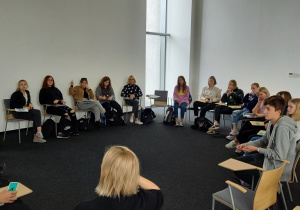 uczniowie siedzą w kręgu przy ławkach jednoosobowych na zajęciach warsztatowych