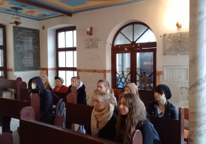 licealiści siedzą w ławkach zasłuchani w opowieści przewodnika Dawida